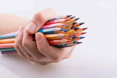 Beyaz arkaplanda el ele tutuşan renkli kalemler