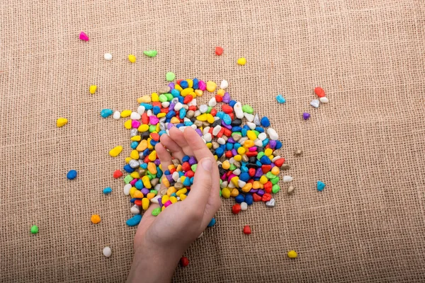 Elindeki ve yerdeki renkli çakıl taşları