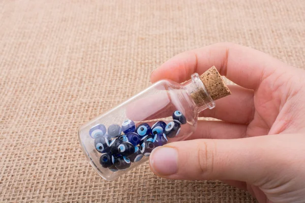 Hatıra olarak şişede nazar boncuğu tutan el.