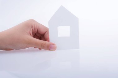 Beyaz bir arka plan üzerinde bir kağıt ev tutan el