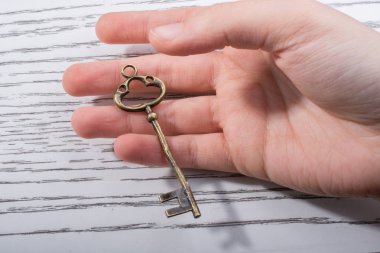 Ahşap doku üzerinde bir retro tasarımlı dekoratif anahtar tutan el