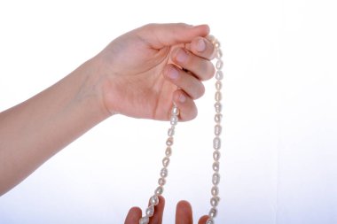 Bir inci kolye beyaz bir arka plan üzerinde tutan el