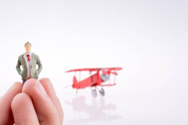 Beyaz bir arka plan üzerinde kırmızı bir insan figürü uçakla tutan el