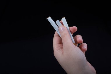 Siyah arka planda sigara tutan bir el var.