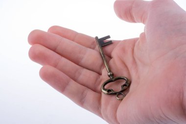 Beyaz arka planda eski moda metal bir anahtar tutan el.