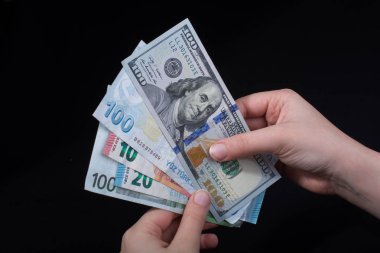El ele tutuşan Amerikan doları banknotları siyah arka planda izole edilmiş.