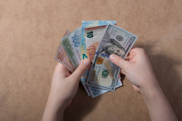 Hand holding American dollar  and Euro banknotes  on wooden background