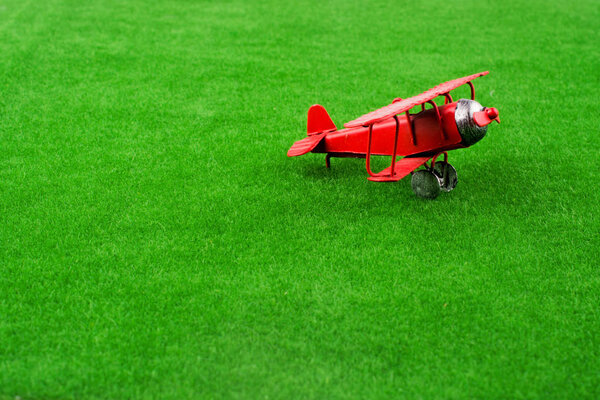 Red little retro model airplane in green grass