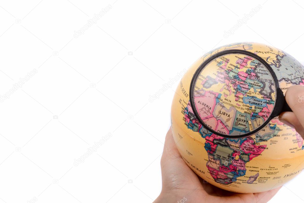 Hand holding a magnifying glass on globe in hand on white background
