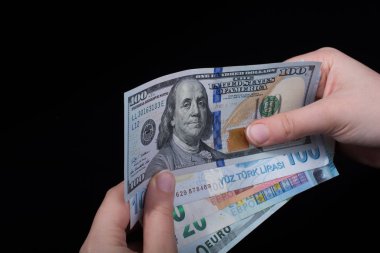 El ele tutuşan Amerikan doları banknotları siyah arka planda izole edilmiş.