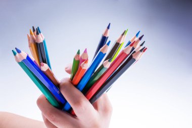 Beyaz arkaplanda el ele tutuşan renkli kalemler