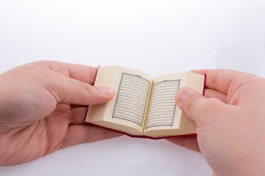 Beyaz arka planda Kuran 'ı el ele tutuşarak.