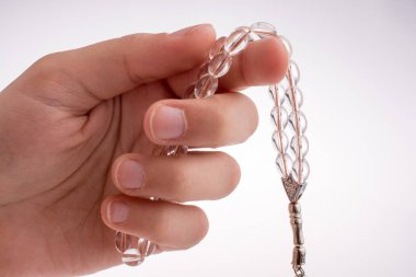 Beyaz bir arka plan üzerinde bir tespih tutan el