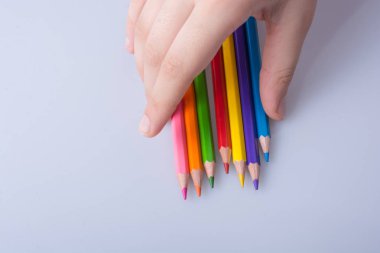 Beyaz arkaplana yerleştirilmiş el ele tutuşan kalemler