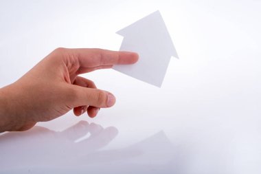 Beyaz bir arka plan üzerinde bir kağıt ev tutan el