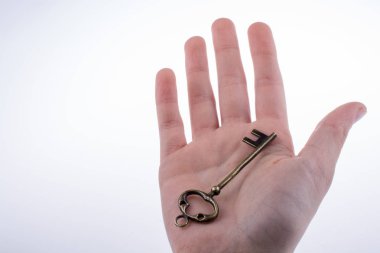 Beyaz arka planda eski moda metal bir anahtar tutan el.