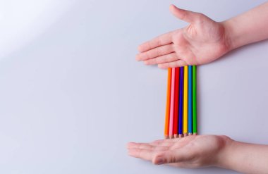 Beyaz arkaplana yerleştirilmiş el ele tutuşan kalemler