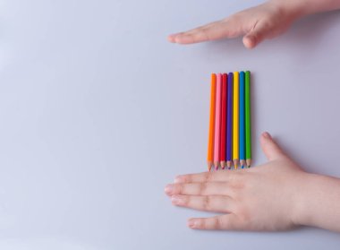 Beyaz arkaplana yerleştirilmiş el ele tutuşan kalemler