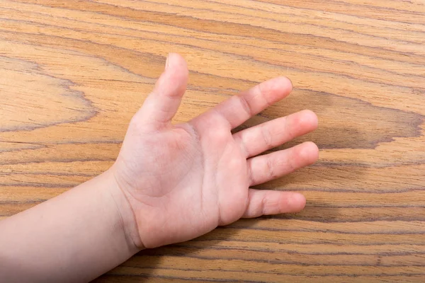 Toddlers hand open with five fingers on wooden texture