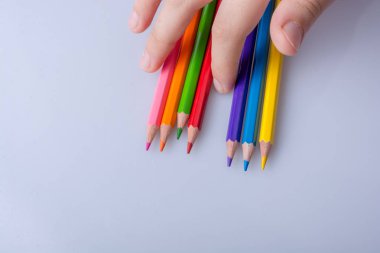 Beyaz arkaplana yerleştirilmiş el ele tutuşan kalemler