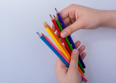 Beyaz arkaplana yerleştirilmiş el ele tutuşan kalemler