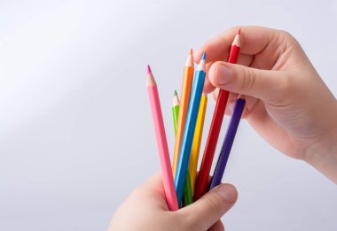 Beyaz arkaplana yerleştirilmiş el ele tutuşan kalemler