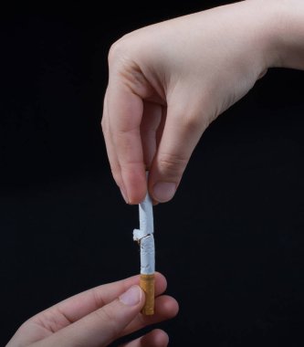 El siyah arka planda sigara kırıyor.