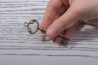 Ahşap doku üzerinde bir retro tasarımlı dekoratif anahtar tutan el