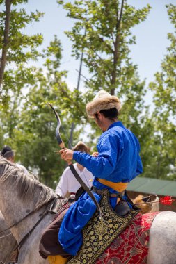 Okçu yay ve geleneksel kıyafetlerle ok atıyor.