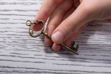 Ahşap doku üzerinde bir retro tasarımlı dekoratif anahtar tutan el