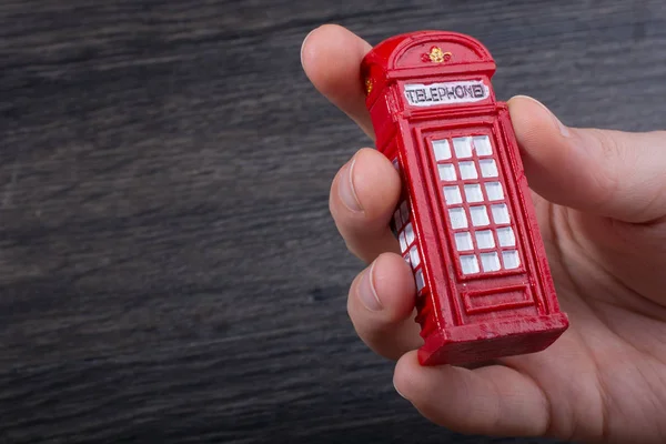 Hand holding a phone booth on a brown background