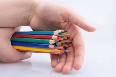 Beyaz arkaplanda el ele tutuşan renkli kalemler