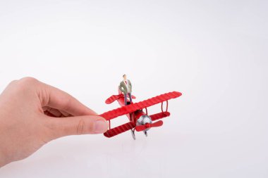 Beyaz bir arka plan üzerinde kırmızı bir insan figürü uçakla tutan el