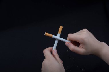 El, siyah arka planda çapraz sigara tutuyor.