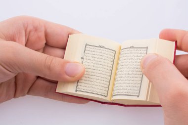 Beyaz arka planda Kuran 'ı el ele tutuşarak.
