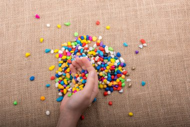 Elindeki ve yerdeki renkli çakıl taşları