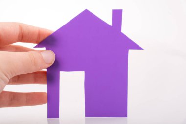 Beyaz bir arka plan üzerinde bir kağıt ev tutan el