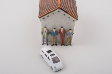 Evin ve arabanın yanında minyatür erkek figürleri.