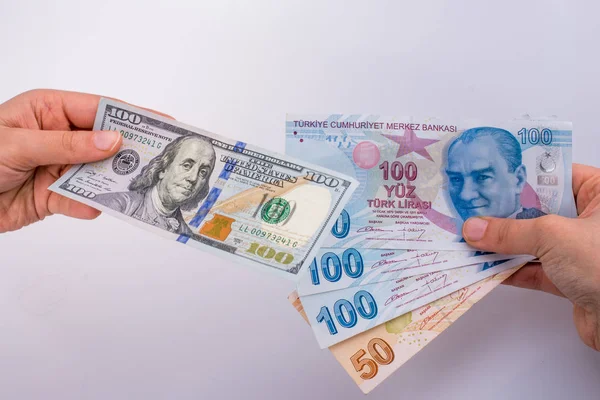 Beyaz arka planda Amerikan doları banknotları ve Türkçe Lira banknotları tutan kişi