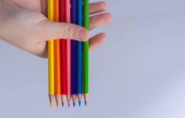 Beyaz arkaplana yerleştirilmiş el ele tutuşan kalemler