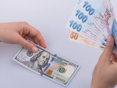 Beyaz arka planda Amerikan doları banknotları ve Türkçe Lira banknotları tutan kişi