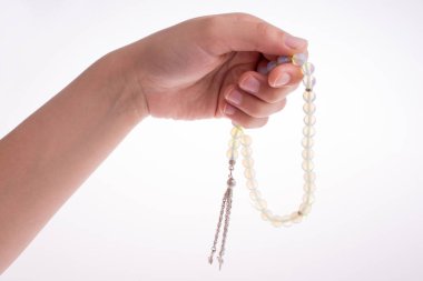 Beyaz bir arka plan üzerinde bir tespih tutan el