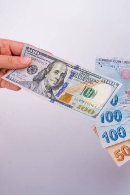 Beyaz arka planda Amerikan doları banknotları ve Türkçe Lira banknotları tutan kişi
