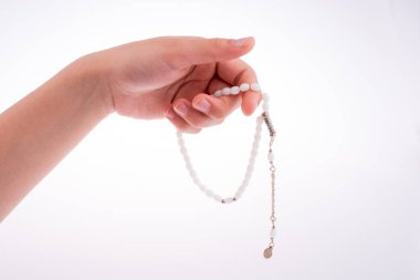 Beyaz bir arka plan üzerinde bir tespih tutan el