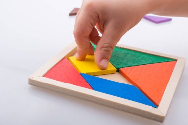 Tangram bulmacasının kayıp parçasını tutan el.
