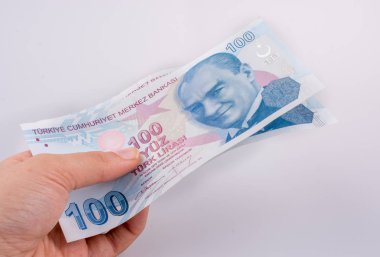 Beyaz arka plan üzerinde 100 Turksh Lirası banknotlar tutan el