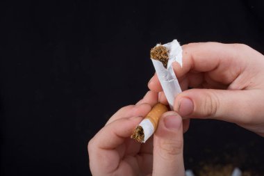 El siyah arka planda sigara kırıyor.