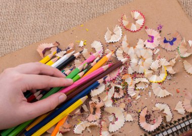 Bir defter kalem talaş ile üzerinde renkli kalemler tutan el