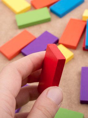 Çeşitli renklerin ahşap bloklarından birini tutarken
