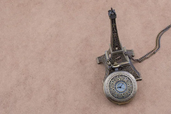 少しモデルのエッフェル塔と茶色の背景に懐中時計 — ストック写真